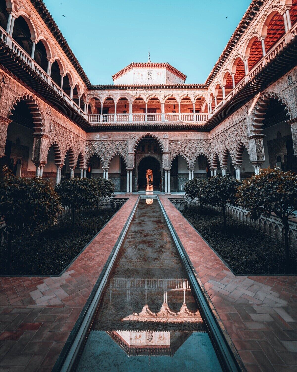 A courtyard with a central water feature, surrounded by arches and a tiled roof.