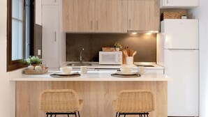 A modern kitchen with a central island, two bar stools, pendant lighting, and a refrigerator. - Home2Book Amelia's Pottery, Triana (Sevilla)