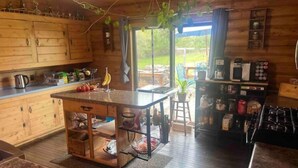 Cocina de cabaña de madera con una isla central, armarios de madera y una estufa.