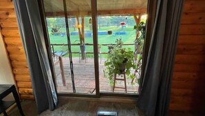 Una habitación con puerta corrediza de vidrio que da a un espacio exterior con jardín y terraza de madera.
