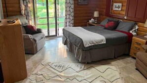Un dormitorio con cama, sofá, mesita de noche y armario de madera.