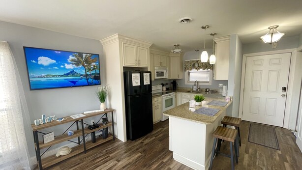 A modern kitchen with white cabinetry, a black refrigerator, and a wooden island. - Cherry Grove 2 bedroom condo, just a block off the beach.  (North Myrtle Beach)