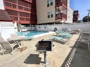 A pool area with lounge chairs and a barbecue grill. - Cherry Grove 2 bedroom condo, just a block off the beach. (North Myrtle Beach)
