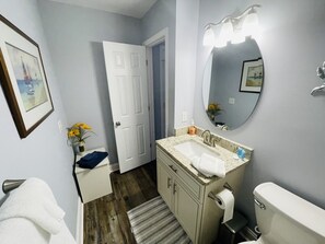 A bathroom with a sink, mirror, toilet, and a door. - Cherry Grove 2 bedroom condo, just a block off the beach. (North Myrtle Beach)