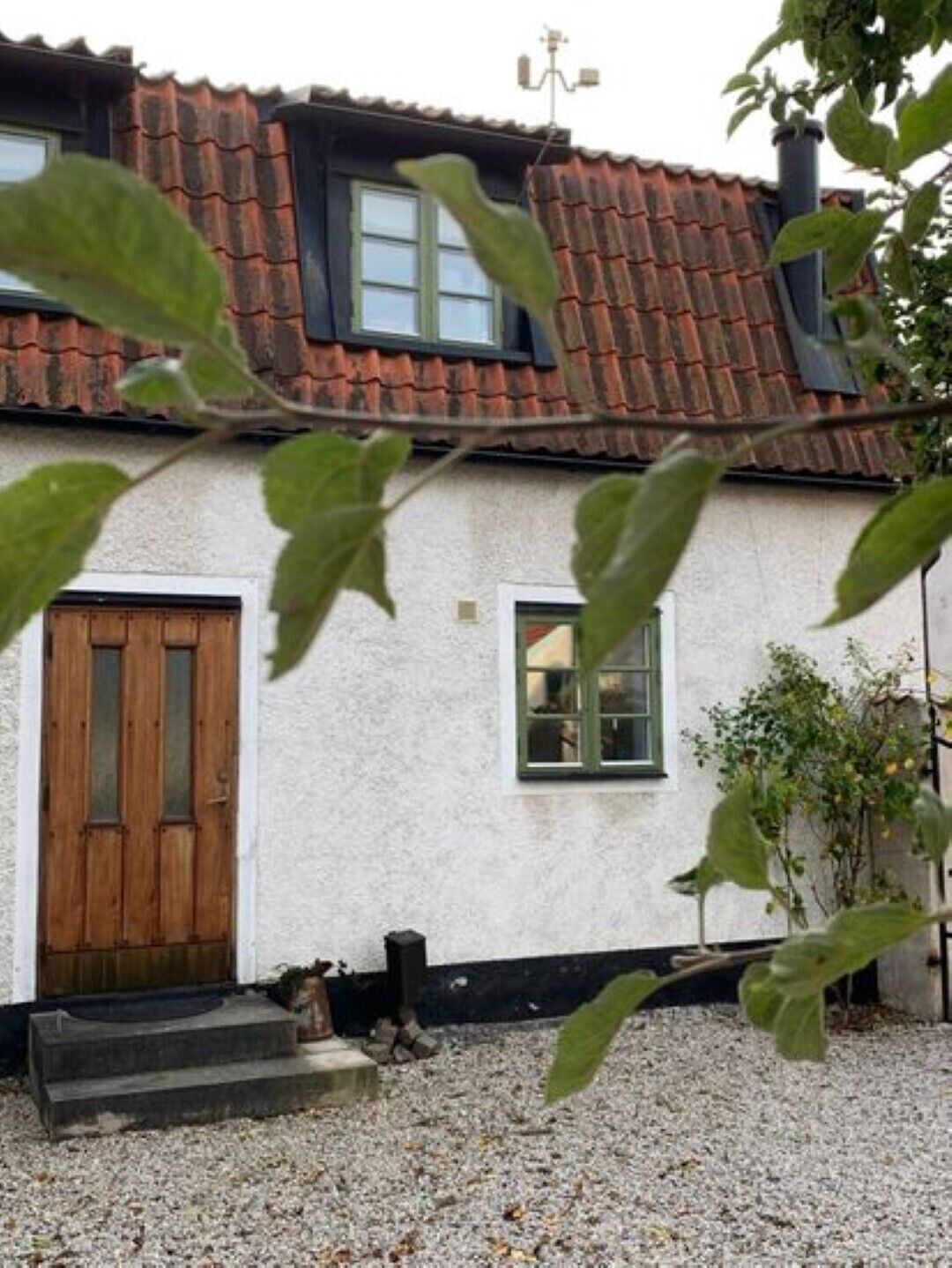 Een huis met een rode pannendak, een houten deur en een klein raam.