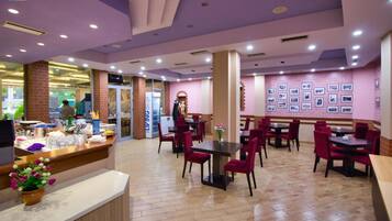 A restaurant with a counter, red chairs, and a wall with framed pictures.