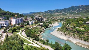A river flowing through a town with buildings and mountains in the background. - Hotel Alvero (Përmet)