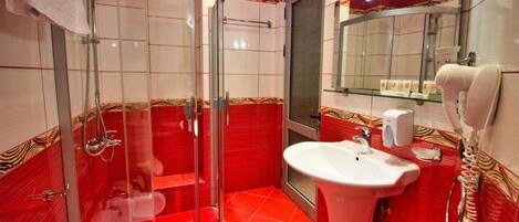 A bathroom with a glass shower enclosure, a sink, and a mirror.
