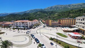 Un hotel con un patio central, rodeado de edificios, y montañas al fondo.