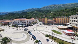 A hotel with a central courtyard, surrounded by buildings, and a mountainous backdrop. - Hotel Alvero (Përmet)