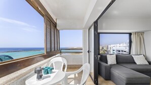 Ein Balkon mit Tisch, Stühlen, einer Couch und Meerblick.