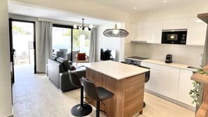 Une cuisine moderne dotée d’un îlot central, de tabourets de bar et d’un coin repas comprenant un canapé et des chaises.