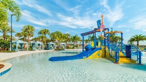 A water park with a blue and yellow play structure, palm trees, and lounge chairs. - Solara Savings 2025 9BR Home w/private pool & games for 18 - Clubhouse Included (Four Corners)