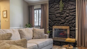 Una sala de estar con pared de piedra, chimenea, sofá y mesa de centro.