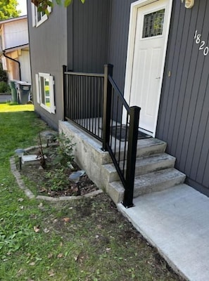 Staircase leads to a welcoming entrance with a well-manicured lawn and garden.