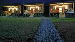 Uma fileira de cabanas de madeira com escadas externas e um caminho de cascalho que as leva.