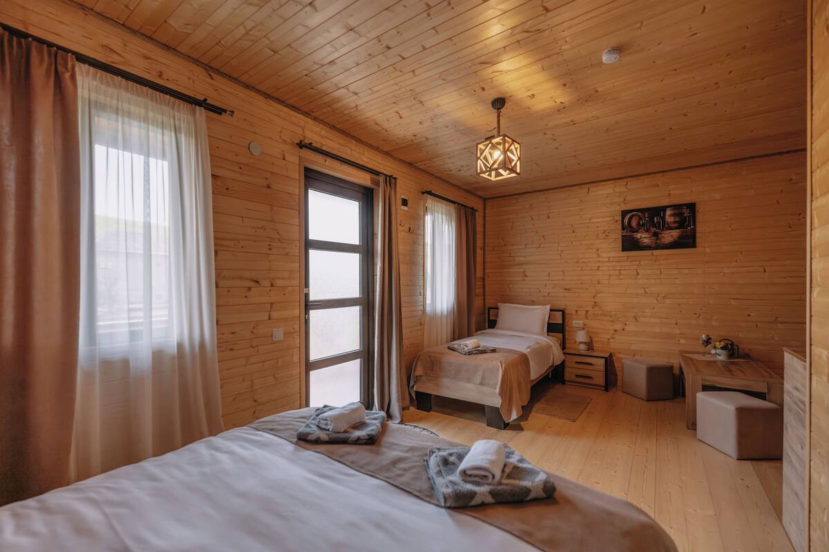 Une pièce de style cabane en bois, avec deux lits, un bureau et un luminaire suspendu.