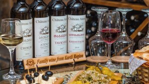 Uma seleção de garrafas e copos de vinho sobre uma mesa, com etiquetas que indicam que são da Região de Kartli.