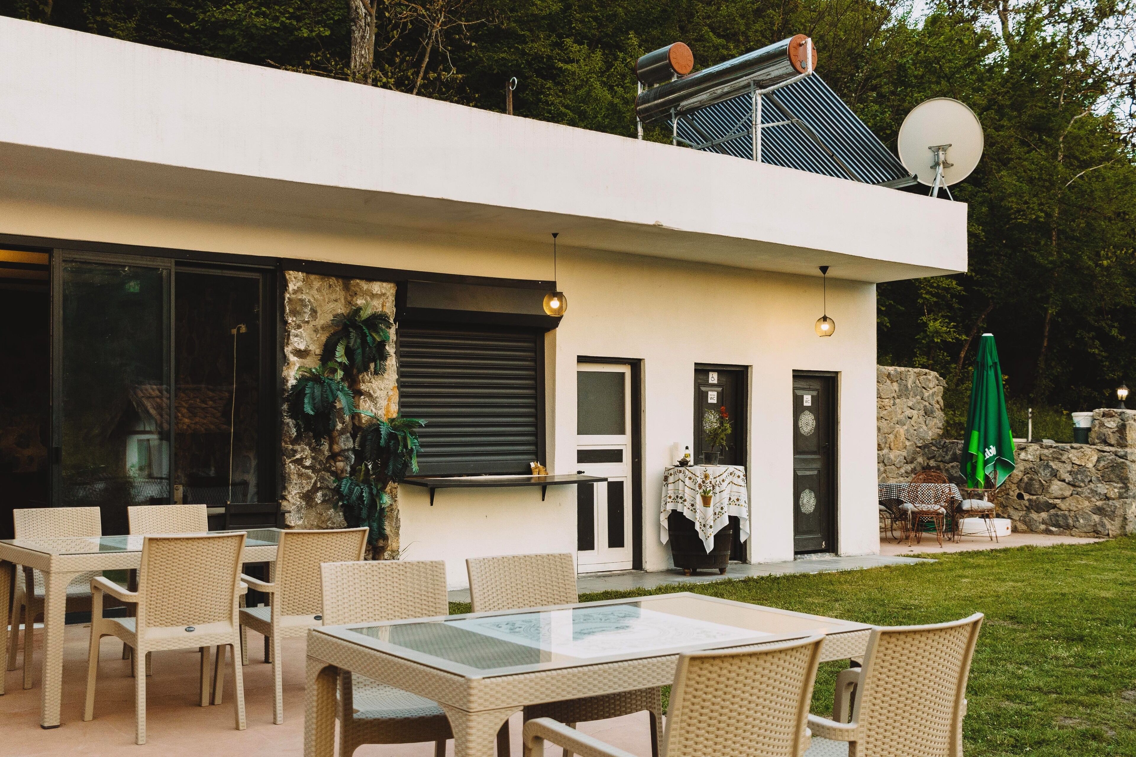 Una casa moderna con mesa de comedor de vidrio, sillas de mimbre, pared de piedra y antena parabólica.