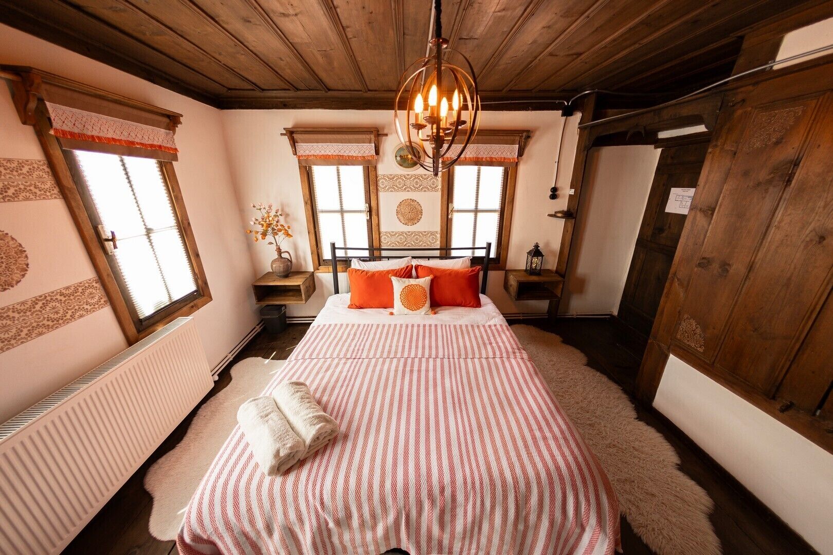 A cozy bedroom with a large bed, wooden ceiling, and a window with a view.