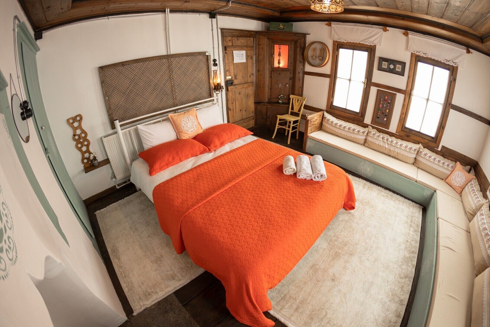 A room with a large bed, a wooden headboard, a small table, and a bench with cushions.