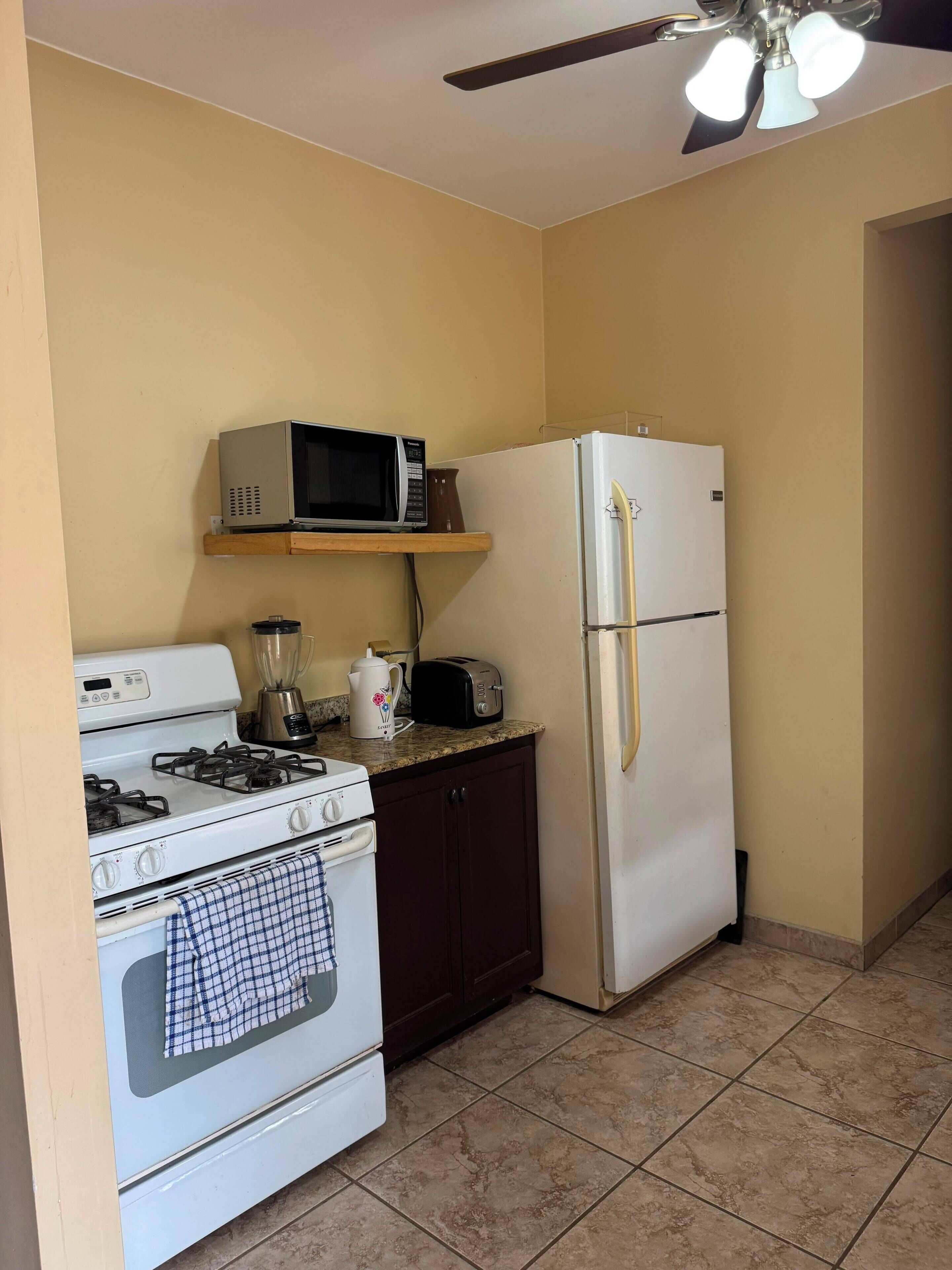 Eine kleine Küche mit Herd, Mikrowelle, Toaster und Kühlschrank.