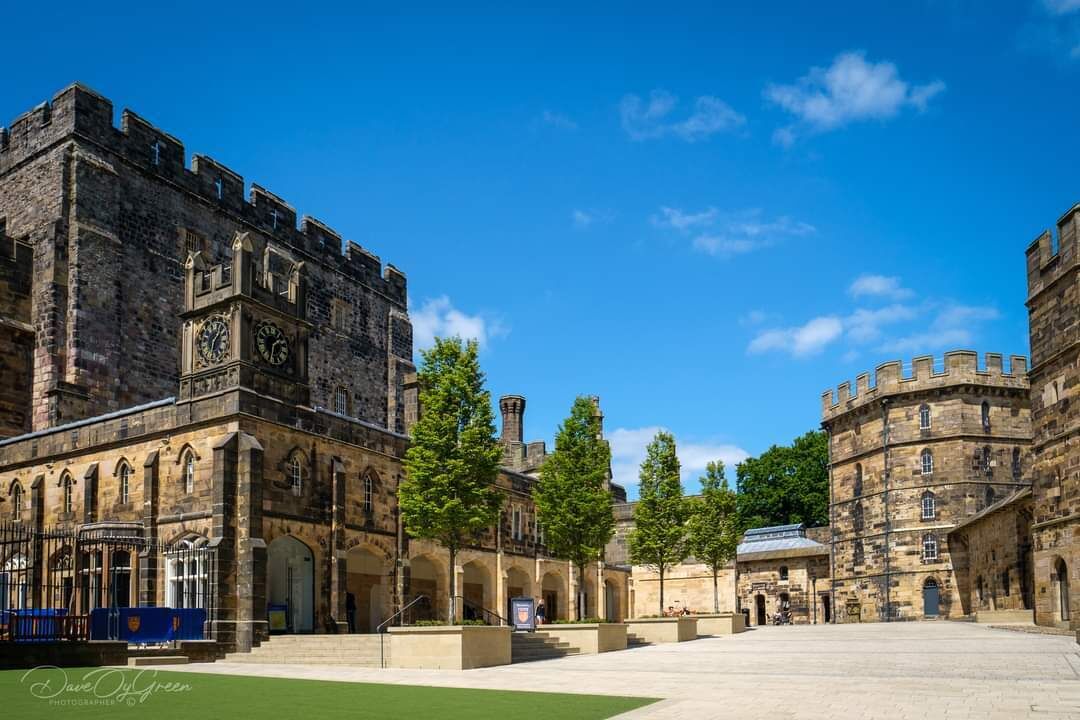A historic building with a large courtyard, stone architecture, and a clock tower.