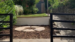 A garden pathway leading to a house with a stone wall and a metal gate. - Spacious Lancaster city centre hide away with garden. (Lancaster)