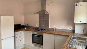 A modern kitchen with a built-in oven, a gas stove, a microwave, and a stainless steel sink. - Spacious Lancaster city centre hide away with garden. (Lancaster)