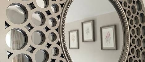 A circular wall decoration with a central mirror surrounded by a decorative metal frame with circular cutouts.