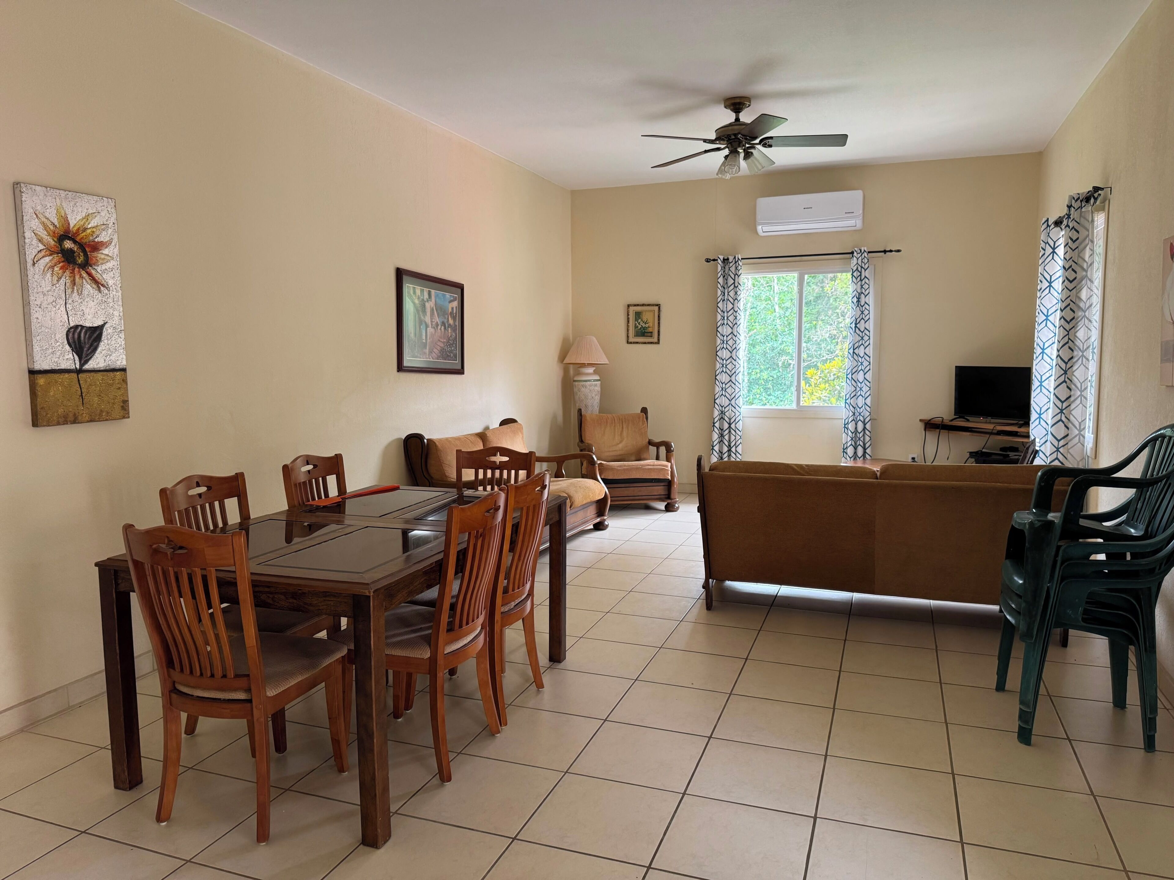 A living room with a dining table, chairs, a sofa, a TV, and a ceiling fan.