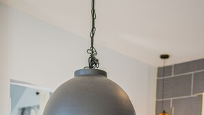 A modern kitchen with a hanging pendant light, a wooden table with a potted plant, and a kitchen island.