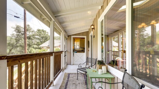 A covered porch with a wooden railing, a green table with chairs, and a view of the backyard. - Lakefront Glen Ellen Cabin w/ Views Near Wineries! (Glen Ellen)