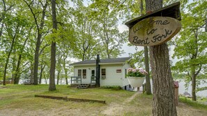 Una cabaña con un letrero que dice 'Welcome to Benton Fork', un muelle y vista al lago.