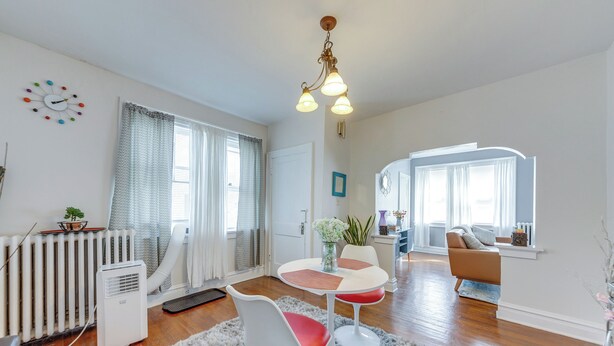 Un salon moderne comprenant un coin repas, un radiateur et une grande fenêtre avec des rideaux.