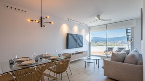 Een moderne woonkamer met een eethoek, een grote televisie en een balkon met uitzicht.