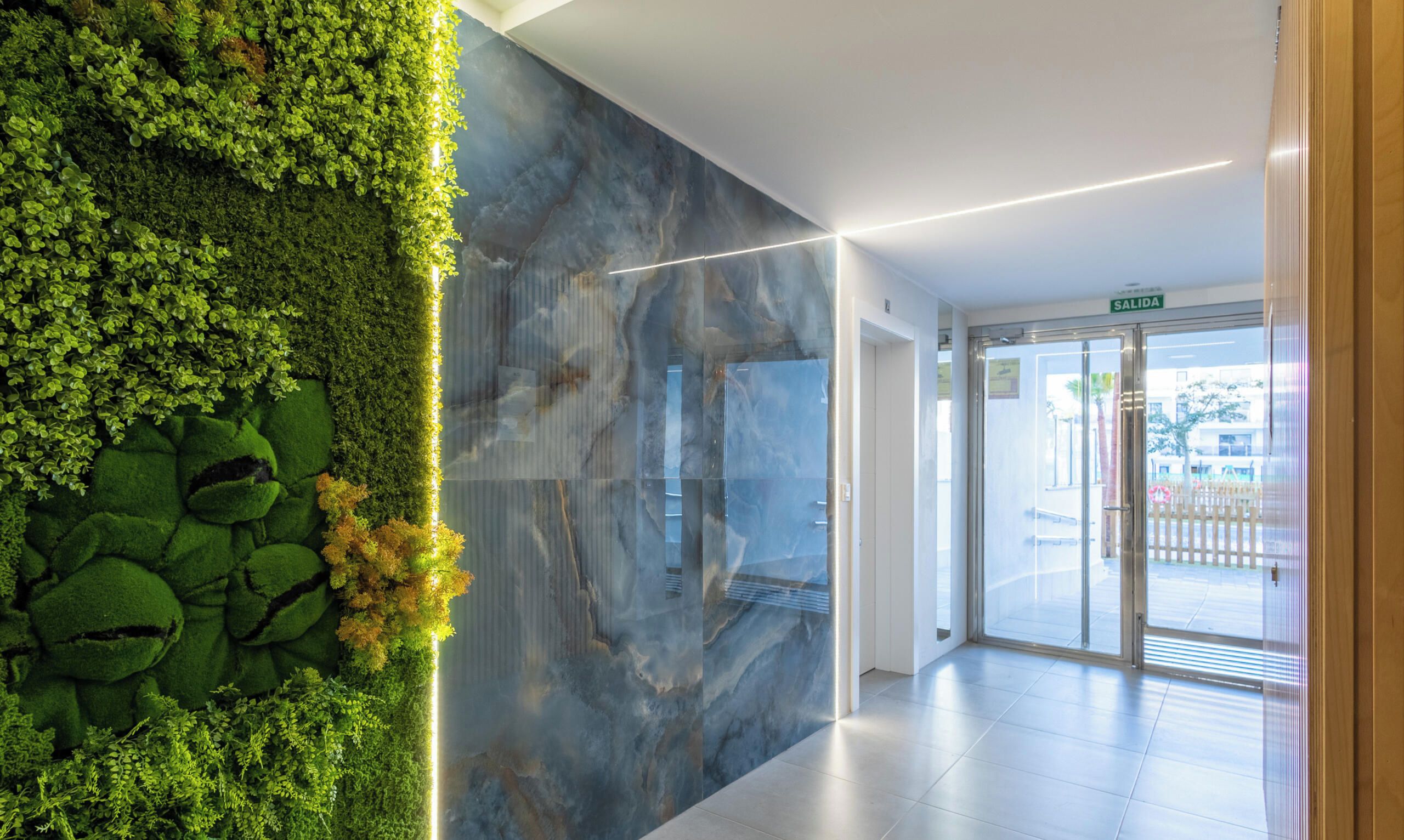 A lobby with a green wall, a marble wall, and a glass door leading outside.