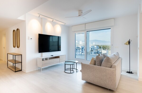 Uma sala de estar moderna com uma TV de tela plana grande, um sofá e um espaço de jantar.