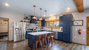 A modern kitchen with a central island, stainless steel appliances, and copper pendant lighting. - Gathering Place: Lakefront w. boat slip | Dog friendly | Hot tub | Fire pit (Oakland)