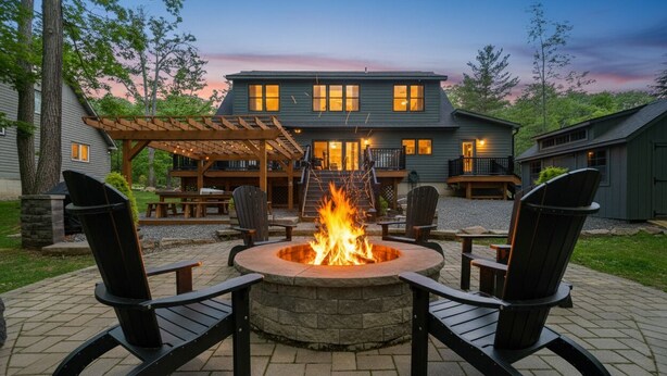 A fire pit with four chairs, a pergola, and a house in the background. - Gathering Place: Lakefront w. boat slip | Dog friendly | Hot tub | Fire pit (Oakland)