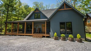 A two-story cabin with a porch, a covered area, and a gravel driveway. - Gathering Place: Lakefront w. boat slip | Dog friendly | Hot tub | Fire pit (Oakland)