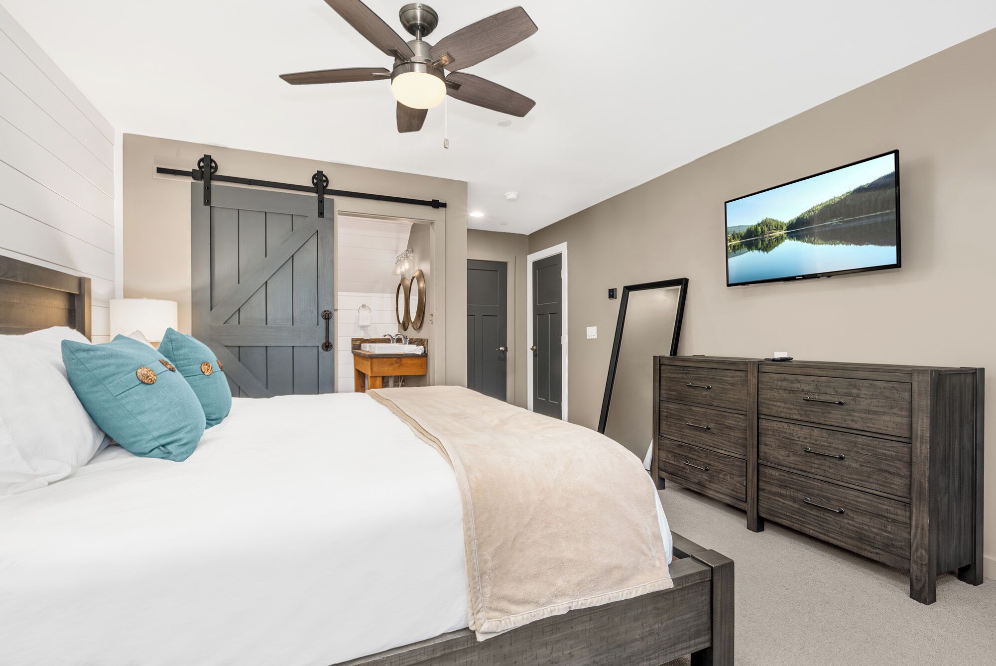 Une chambre à coucher avec un lit, une commode, un téléviseur et un ventilateur de plafond.