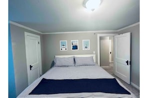 Une chambre à coucher avec un lit, deux portes et trois tableaux encadrés accrochés au mur.