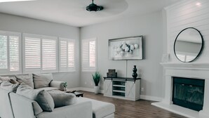 A modern living room with a sectional sofa, a fireplace, a mounted TV, and a potted plant.