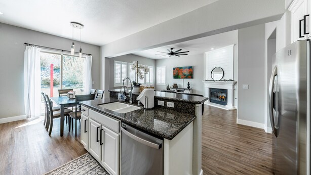 A modern kitchen with granite countertops, stainless steel appliances, and a dining area with a table and chairs.