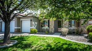 A residential house with a stone facade, a garage, and a well-maintained lawn.
