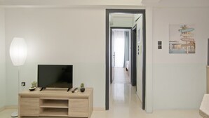 A modern living room with a TV, a lamp, and a console table. A hallway leads to another room.