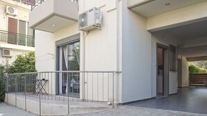 Ein Gebäude mit überdachter Eingangspartei, einer kleinen Außenbestuhlung und einer sichtbaren Klimaanlage.