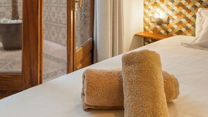 Une chambre d’hôtel avec un lit, une porte en bois, un mur carrelé et une vue sur un espace extérieur.