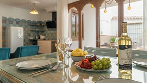 Une table à manger avec des assiettes, des verres et une bouteille de vin, dans une pièce où l’on aperçoit une cuisine au fond.